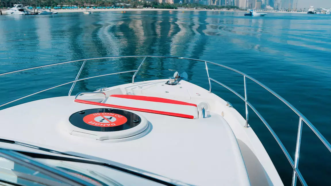 White yacht on a calm blue sea with a city skyline in the distance