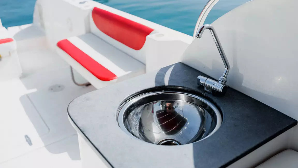 Close-up of a boat's sink with red seat and white exterior, water in the background