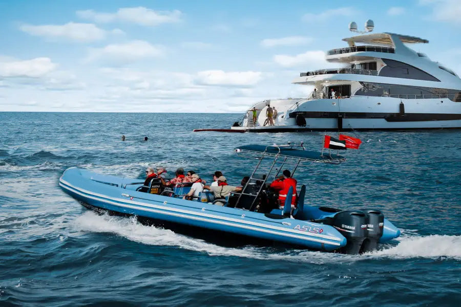 Blue speedboat with passengers near a large yacht on the water