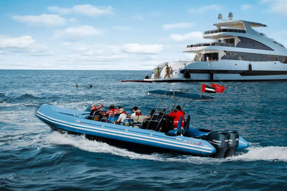 Blue speedboat with passengers near a large yacht on the water