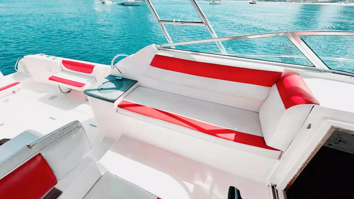 Close-up of a boat's red and white interior seating area with water in the background.