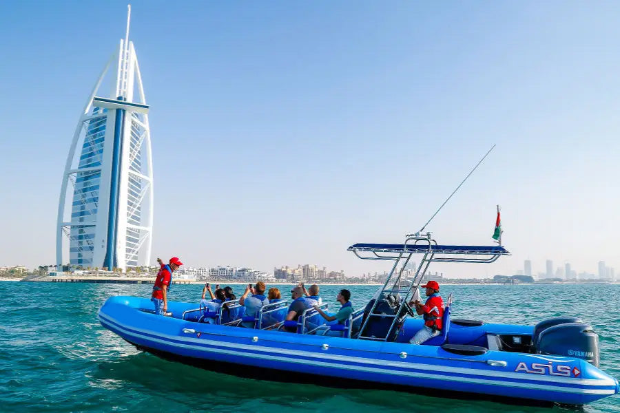 Blue inflatable boat with passengers on a body of water, featuring the Burj Al Arab in the background.