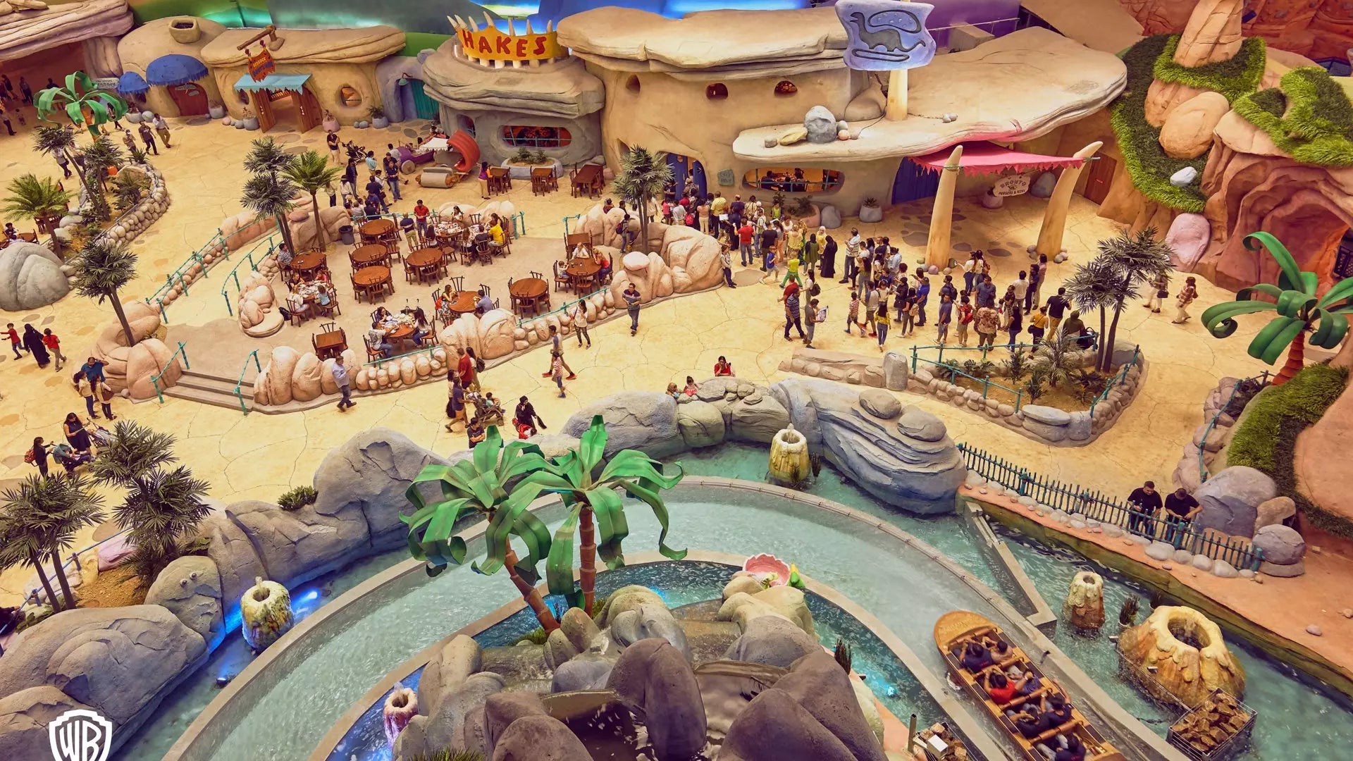 Amusement park with a water ride and visitors in a desert-themed area