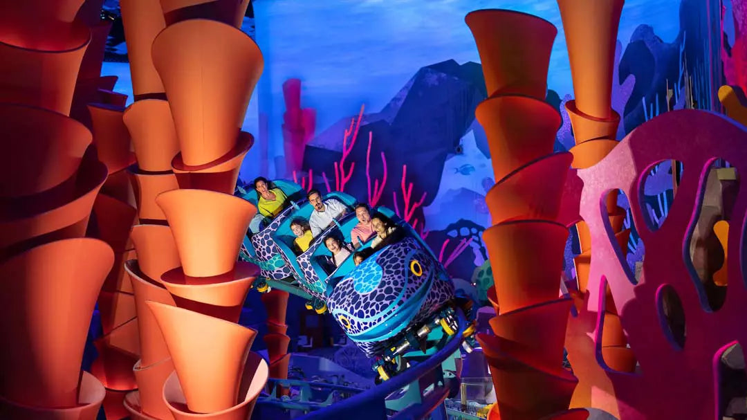 Colorful underwater-themed roller coaster with passengers at a theme park.