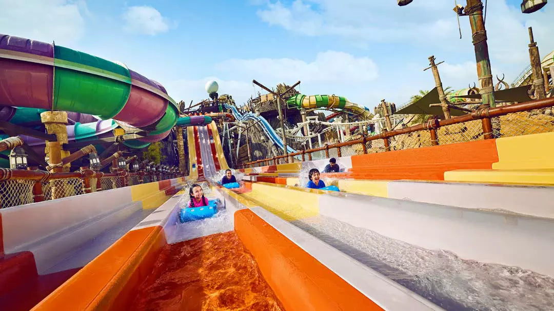Colorful water slide at an amusement park with people sliding down.