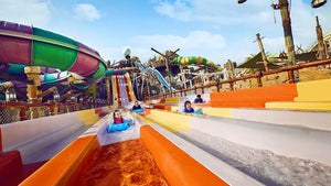 Colorful water slide at an amusement park with people sliding down.