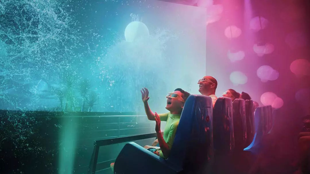 People on a roller coaster with colorful lights and water effects