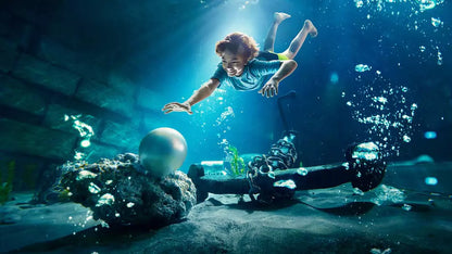 Person swimming underwater with a scuba tank and coral reef