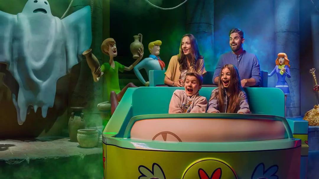 People enjoying a ride in a colorful cartoon-themed amusement park attraction.