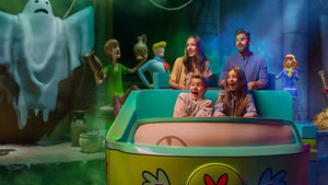 People enjoying a ride in a colorful cartoon-themed amusement park attraction.