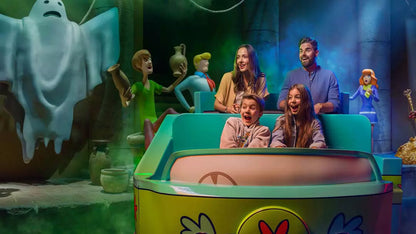 People enjoying a ride in a colorful cartoon-themed amusement park attraction.