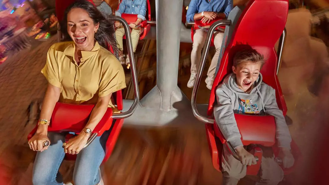 People enjoying a ride on a red amusement park attraction.