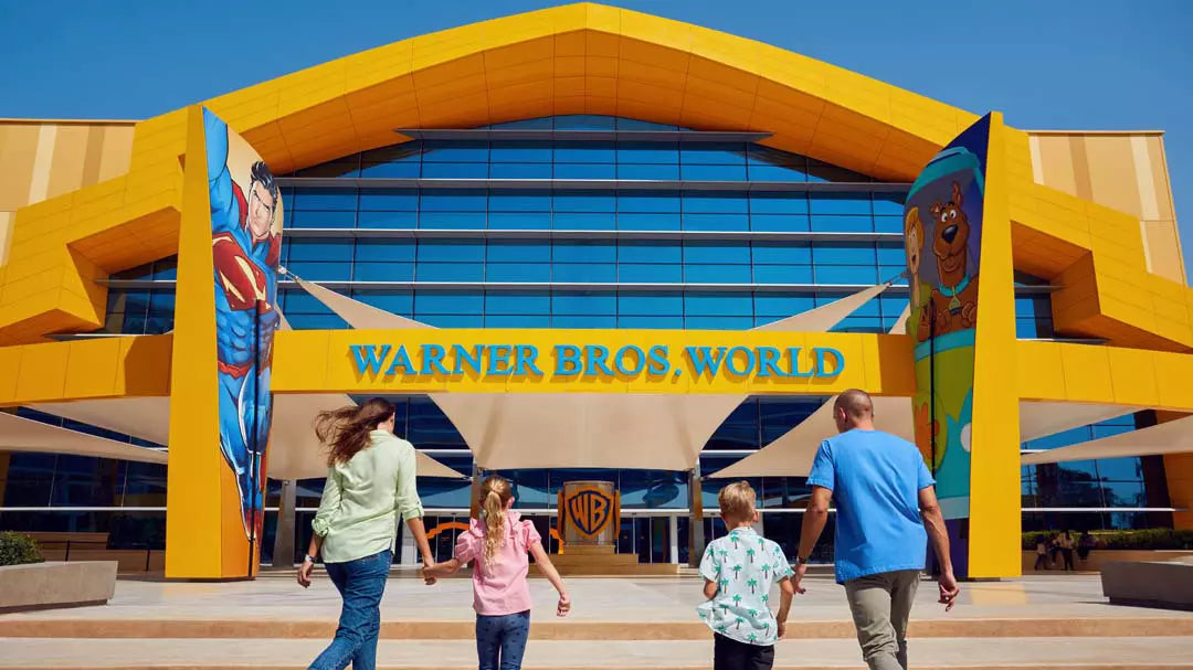 Family walking towards the Warner Bros. World entrance with colorful architecture.