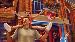 Man carrying a child on his shoulders in front of a theater marquee
