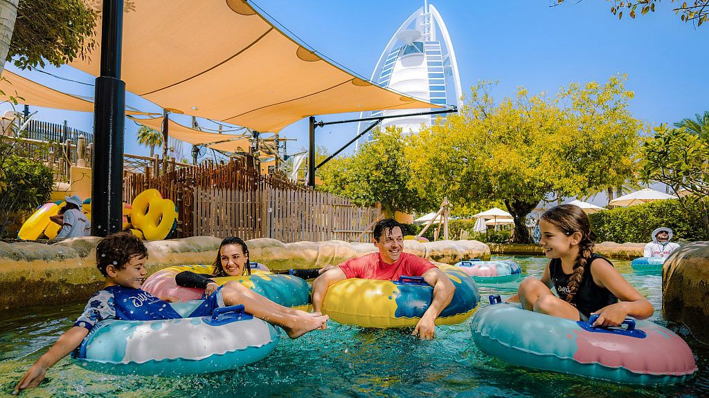 Children on inflatable rings in a pool with a scenic background