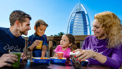 Family of four enjoying drinks with a modern building in the background
