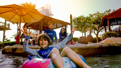 Child on an inflatable ring in a water park with adults in the background