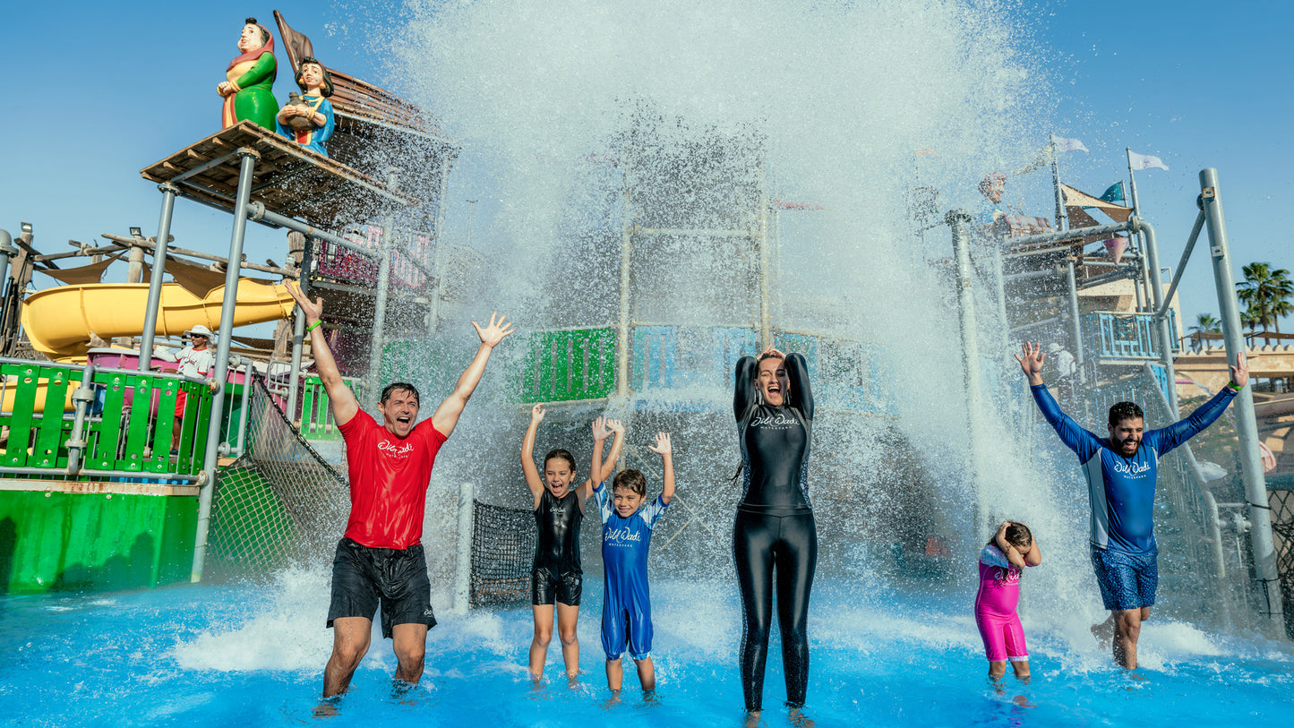 People enjoying a water park with a large splash of water in the foreground